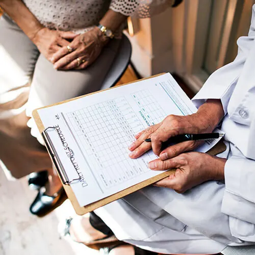 A person in a white coat holding paperwork during a consultation
