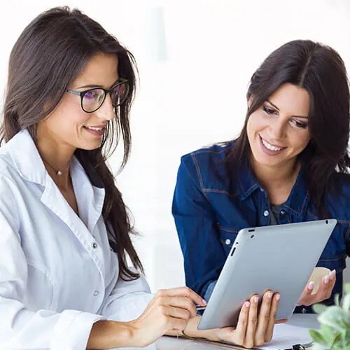 Two women reviewing a tablet in a healthcare setting