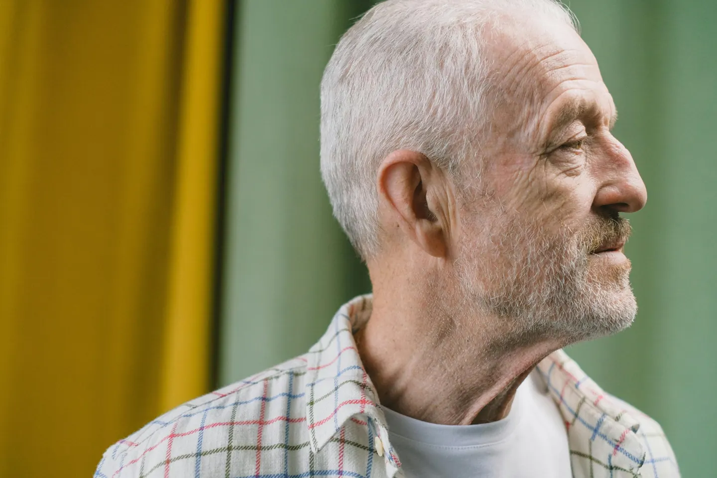 An older man looking to the side indoors