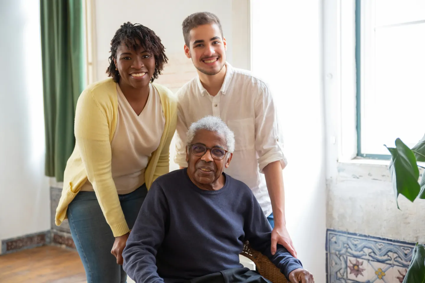 An older man seated with two people standing beside him