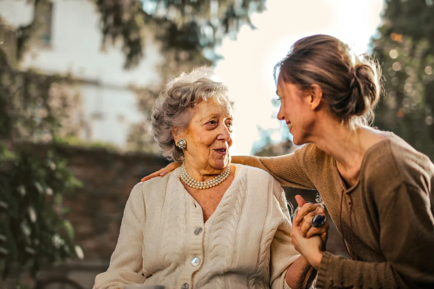 Two women smiling at each other outdoors