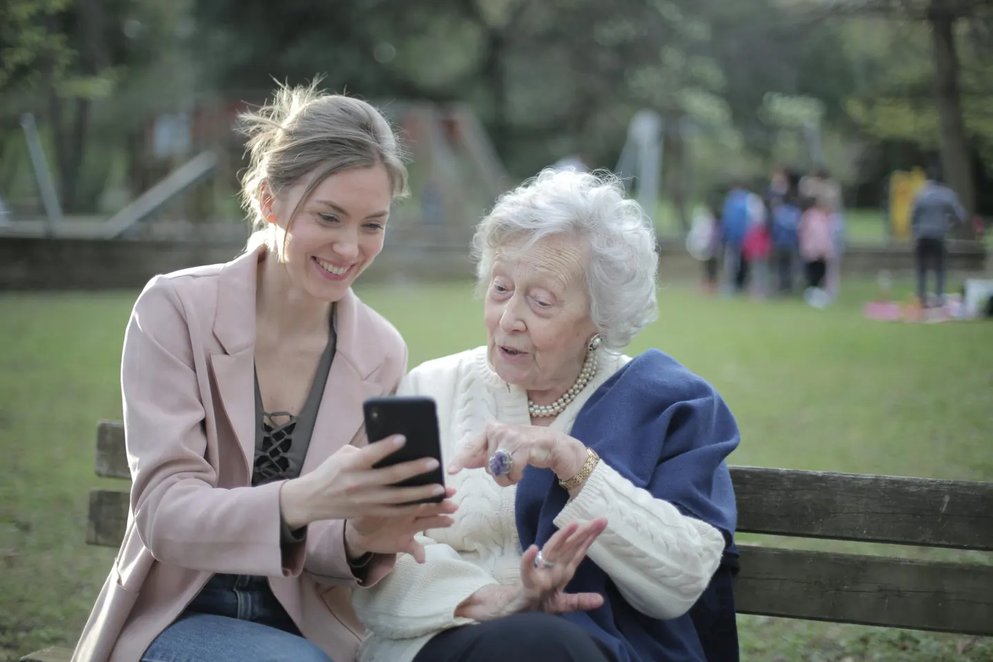 Two women looking at a smartphone in a park