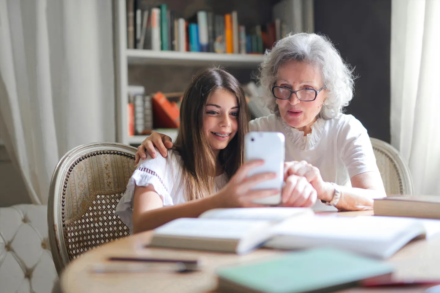 Two women looking at a smartphone at a table